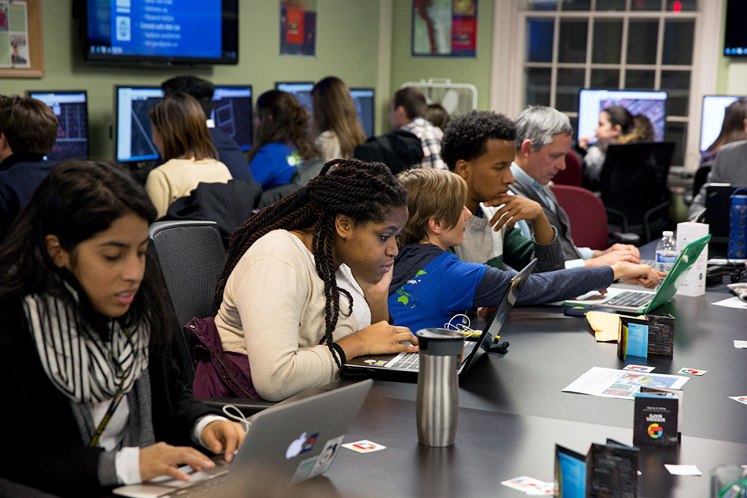 A group of students at a table mapping GPS coordinates on laptops